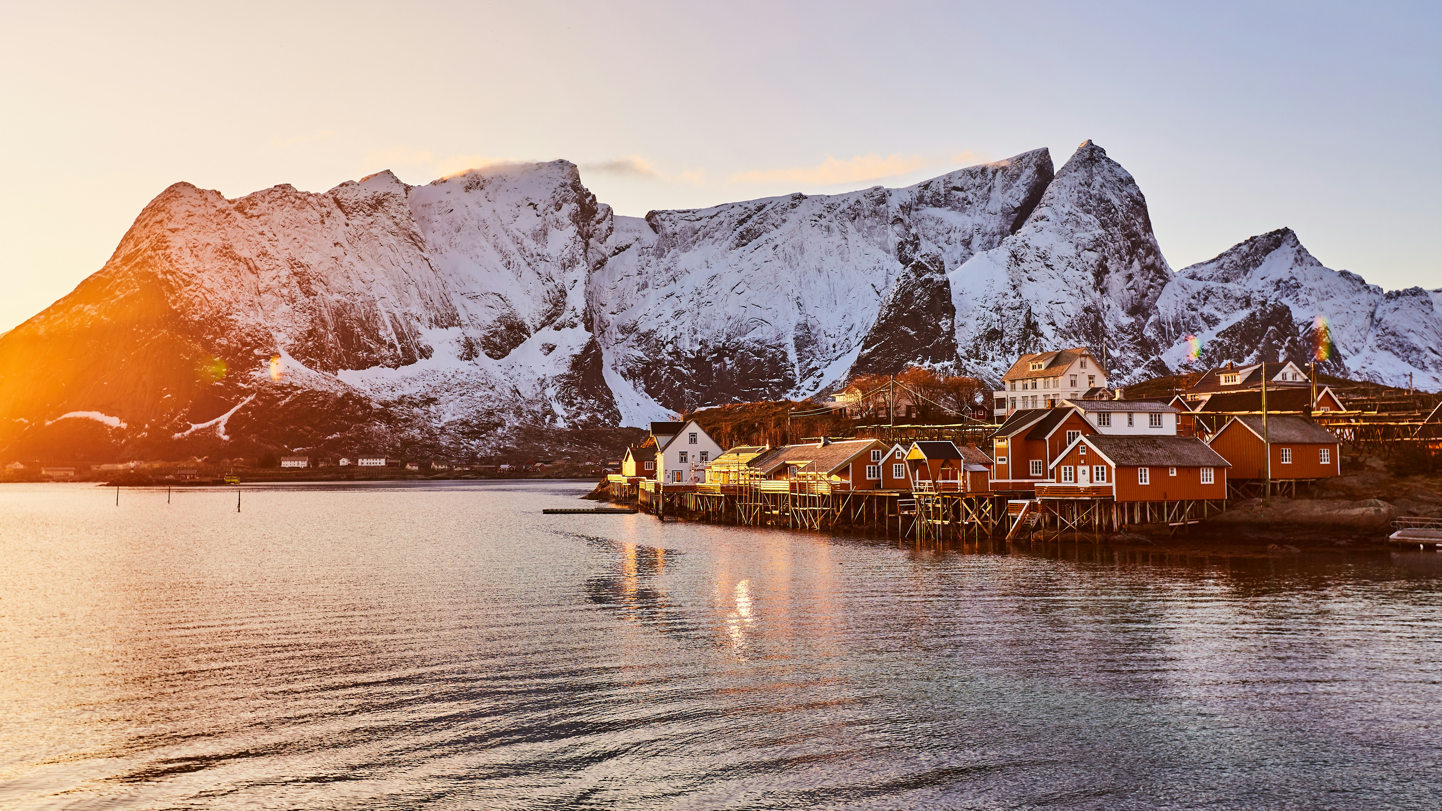 brown wooden house on body of water near mountain during daytime